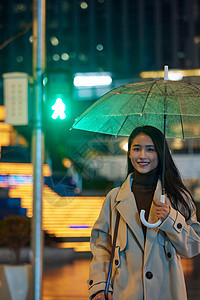 下雨夜晚撑伞过马路的女性图片