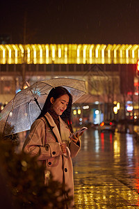 走路下雨天站在路边看手机的女性背景