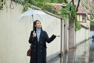 雨天撑伞的女性用手接雨水图片
