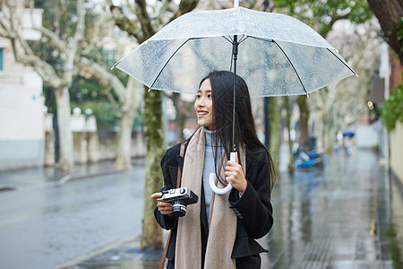 走路下雨天撑着伞的女性手拿照相机背景