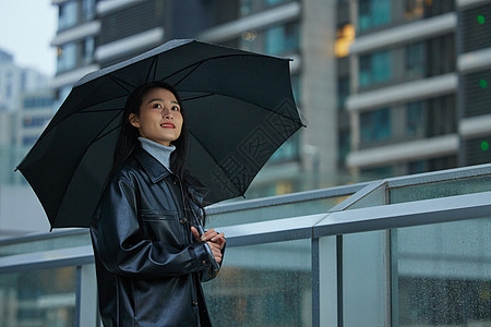 下雨天在城市里行走的女性打伞高清图片素材