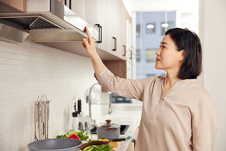 居家女性厨房使用吸油烟机背景图片