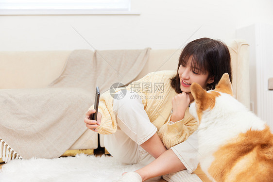 女性用手机和宠物合照图片