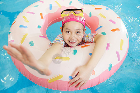 小女孩趴在游泳圈上开心戏水高清图片