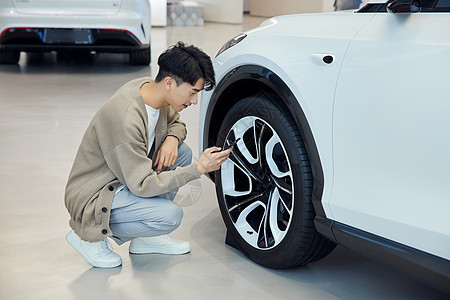 汽车4s店查看轮胎的青年男性背景图片