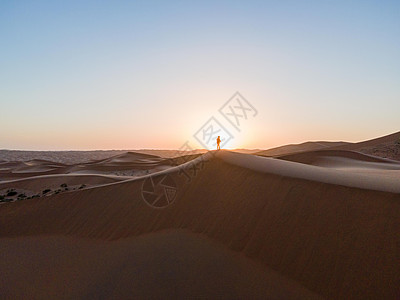 沙漠中徒步的人站在夕阳下图片