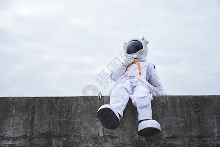 穿着宇航服的男性坐在海边思考图片
