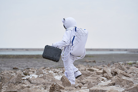 穿着宇航服的男性拿手提箱背影图片
