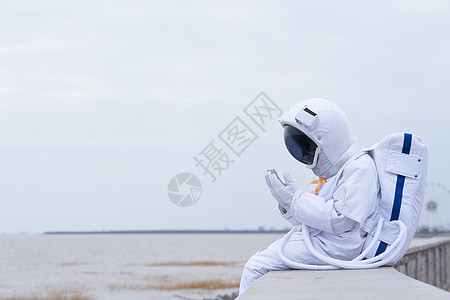 穿着宇航服的男性坐在海边图片