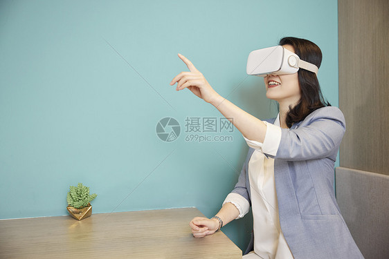 戴VR眼镜的商务女性触碰虚拟屏幕图片