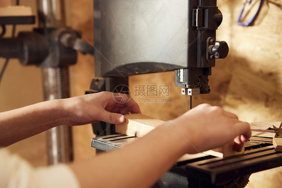 男性工匠使用工具切割木块特写图片