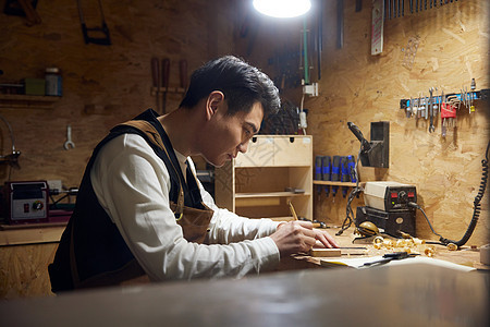 夜晚制作木块的男性工匠图片