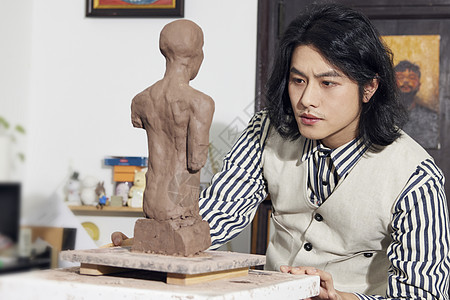 年轻男雕刻家专注雕塑创作图片
