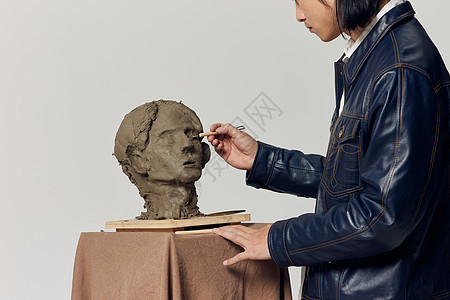 青年男艺术家雕刻泥塑作品特写图片