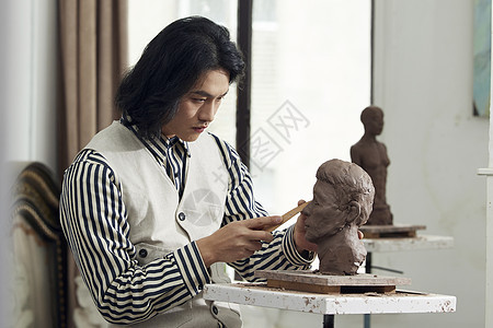 年轻男艺术家专注雕塑形象图片