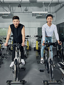 情侣单车动感单车练习的健身男女背景