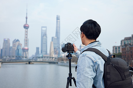 男摄影师使用三脚架拍摄城市风光照图片