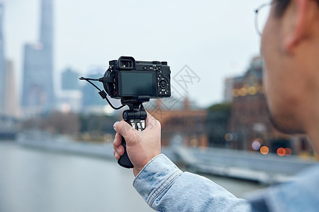 青年男性手拿相机拍摄旅游视频图片