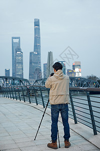 青年男性使用三脚架拍摄城市风光照图片