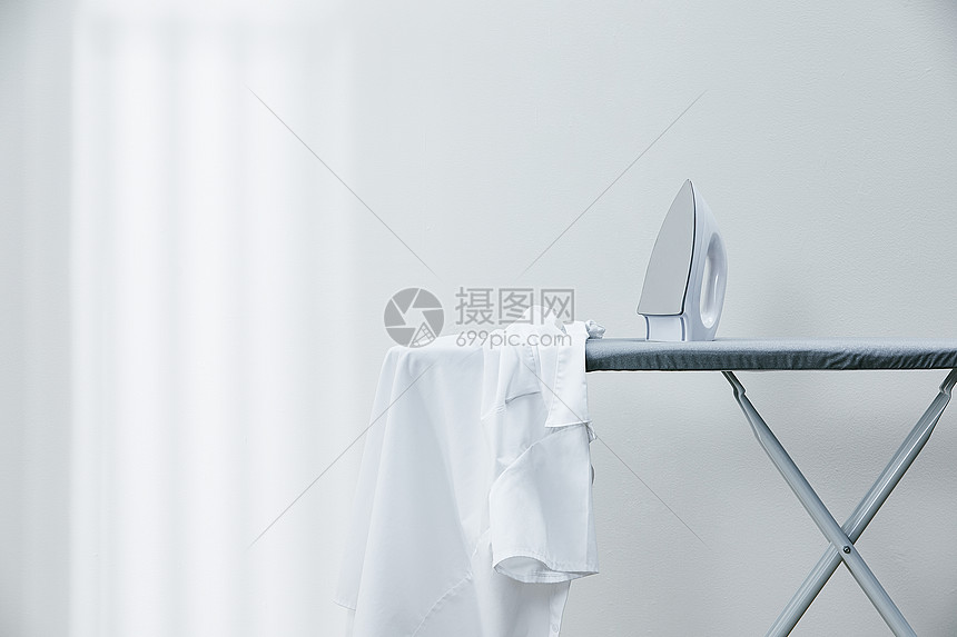 烫衣板上放着的白衬衫和熨斗图片