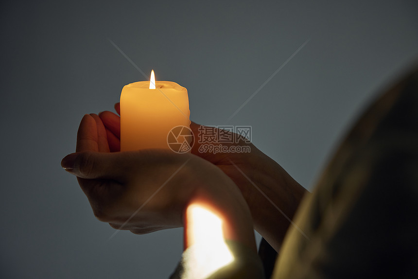 女性手捧祈福蜡烛特写图片