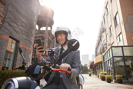 骑电瓶车的商务男青年使用手机图片