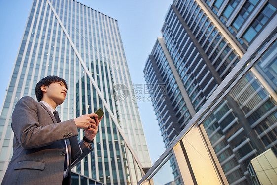 拿着手机仰望城市的男青年图片