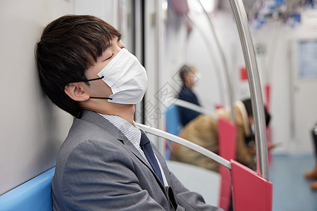 戴着口罩的商务男青年疲惫坐地铁图片