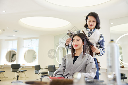 理发师给女性顾客吹头发洗头高清图片素材