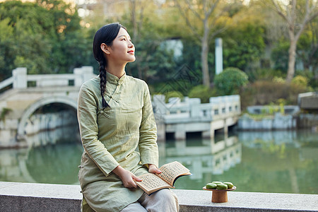 室外看书吃青团的青年女性背景