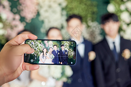 幸福新人和伴郎伴娘用手机拍照记录图片