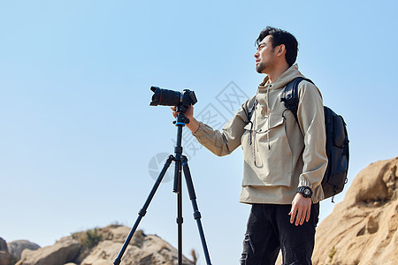 摄影师户外登山使用三脚架拍摄山景背景图片