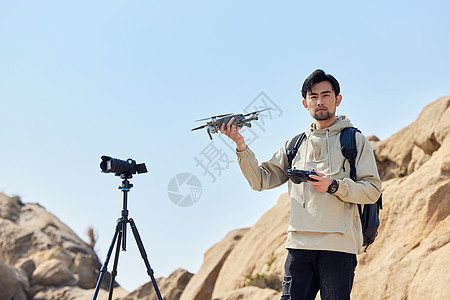 航拍摄影师山顶手拿无人机背景图片