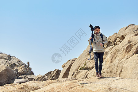 风光摄影师扛三脚架登山堪景背景图片