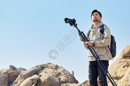 风光摄影师扛三脚架登山堪景背景图片