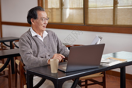 社交电商使用笔记本电脑看书的老年人背景