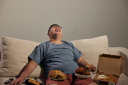 居家肥胖男青年吃夜宵看电视大笑图片
