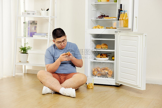 胖男生冰箱前玩手机图片