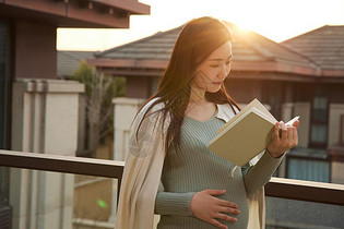 在阳台上休息看书的孕妇妈妈图片