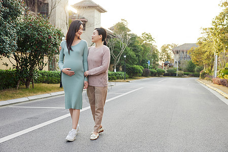 小孩背影妈妈陪怀孕的女儿外出散步背景