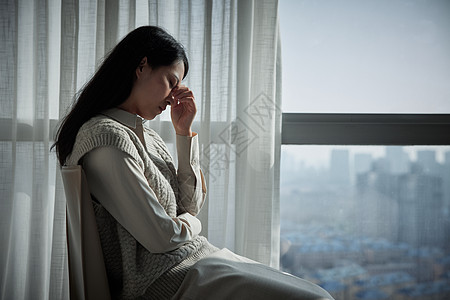 焦虑的女人坐在窗边的抑郁青年女性背景