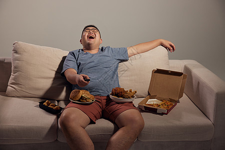 居家肥胖男青年看电视吃夜宵高清图片