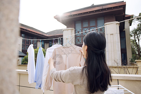 室外家居晾晒衣服的女性形象背景