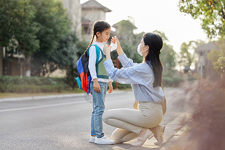 妈妈给上学的女儿戴口罩背景图片