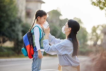 妈妈给上学的女儿戴口罩背景图片