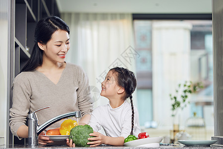 在厨房里一起洗菜的母女背景