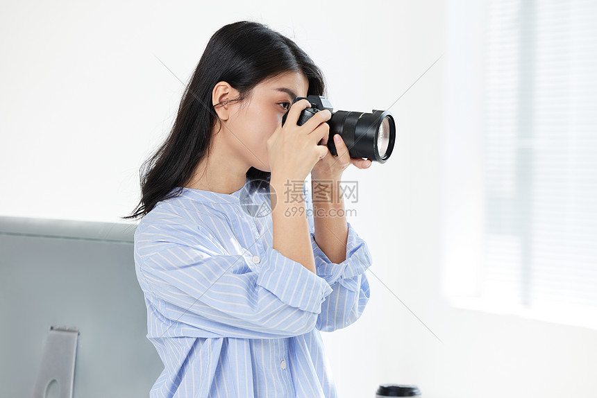 手拿相机拍摄的年轻女摄影师图片
