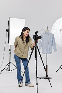 在拍摄服装静物的商业女摄影师图片