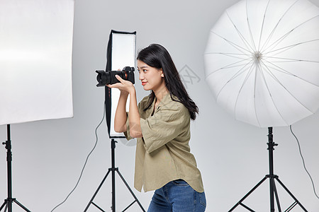 商业女摄影师手拿相机拍摄照片商业摄影高清图片素材