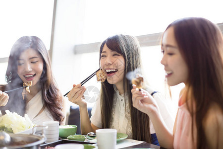 快乐的年轻妇女组吃火锅图片